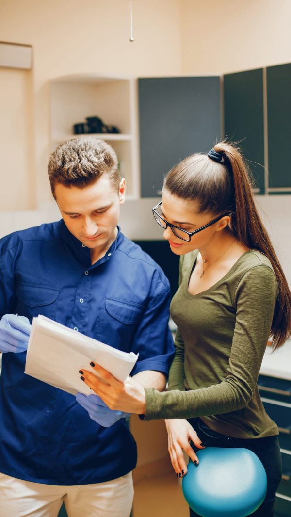 A young and beautiful girl consultes with a dentist in the dentist's office